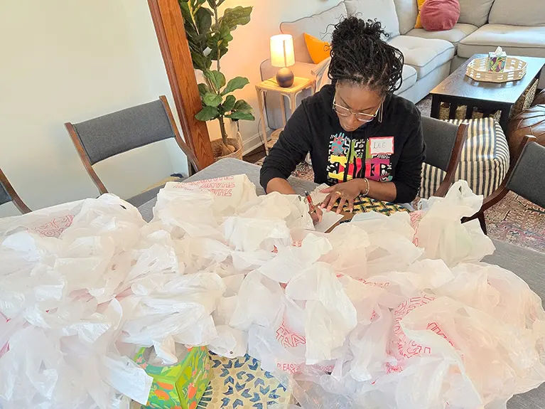 A volunteer sits at a table full of plastic donation bags at Friends of Refugee's Hospitality House.